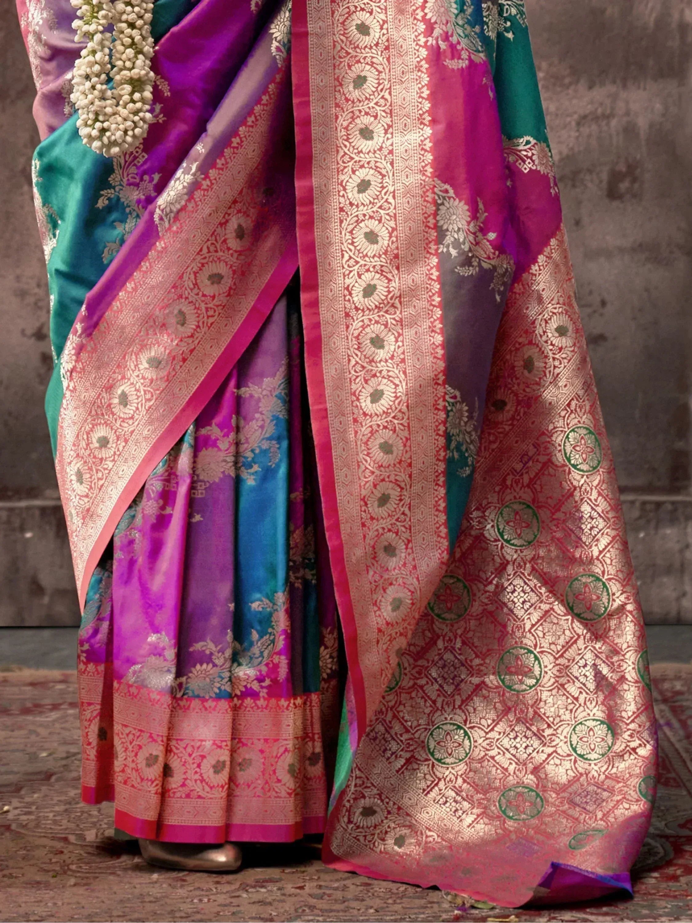 Vibrant purple and teal silk saree with gold zari border and floral motifs, perfect for Indian ethnic occasions.