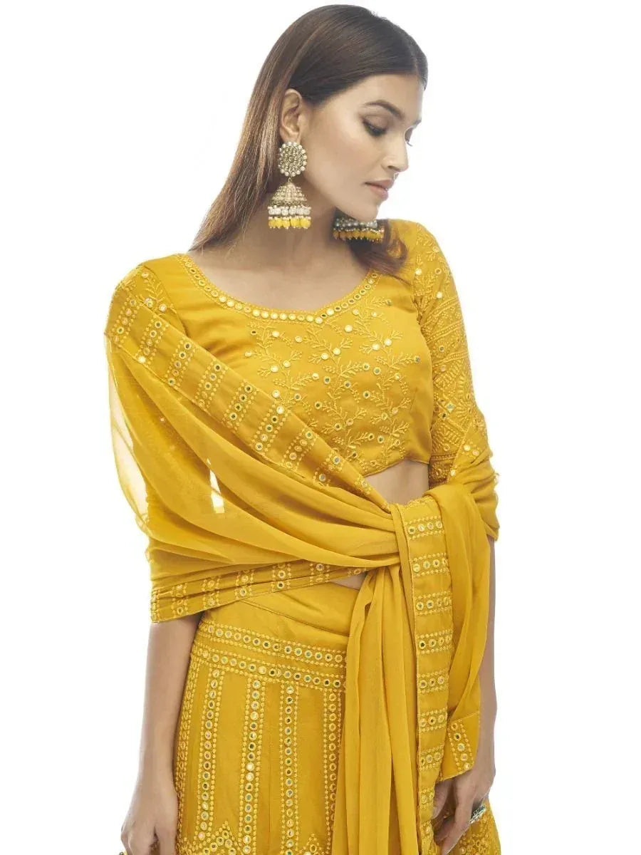 Yellow embroidered ethnic salwar kameez with mirror work and matching dupatta, styled with jhumka earrings