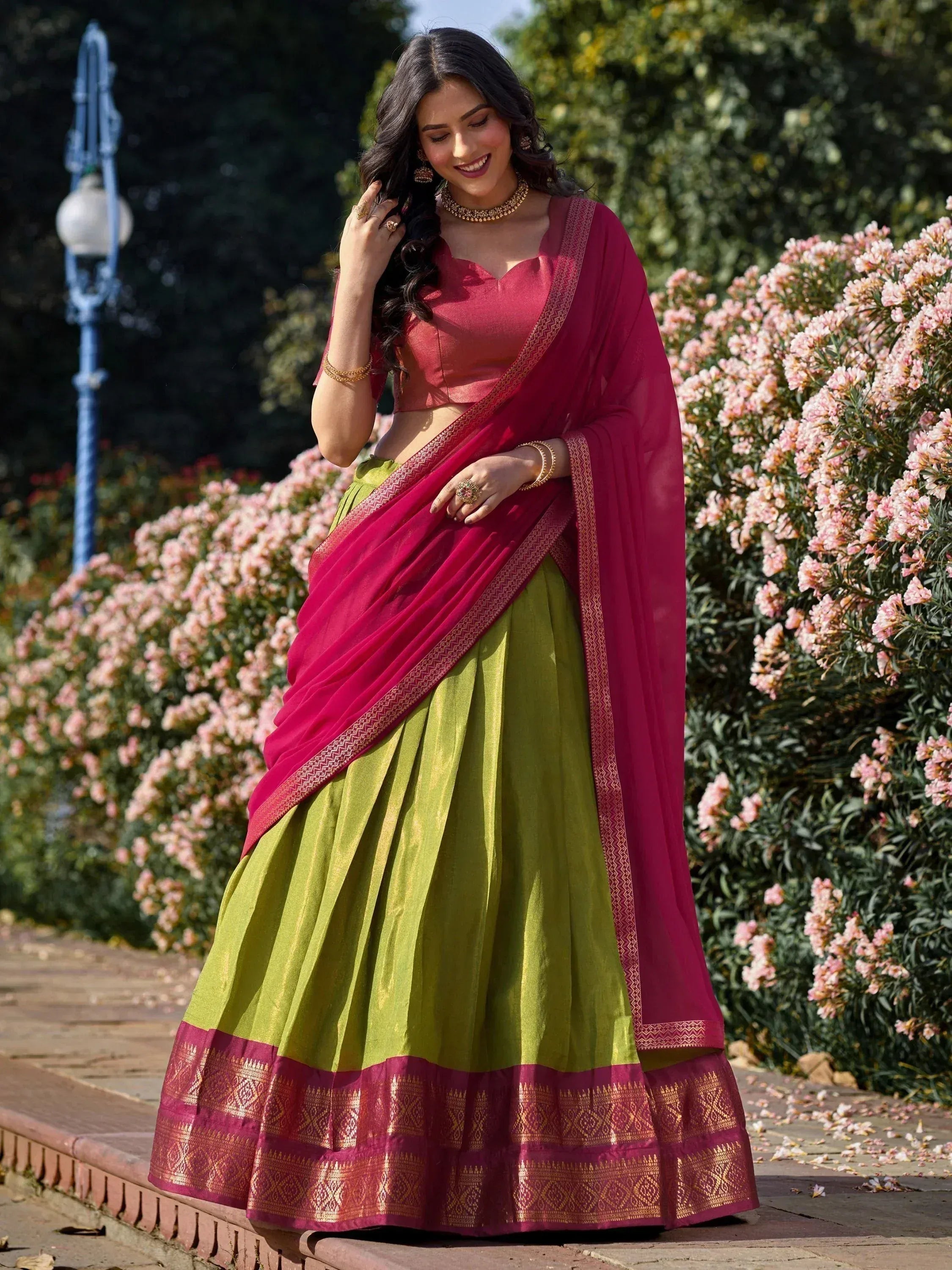 Woman in vibrant green and pink lehenga choli with gold embroidery, perfect for Indian ethnic occasions