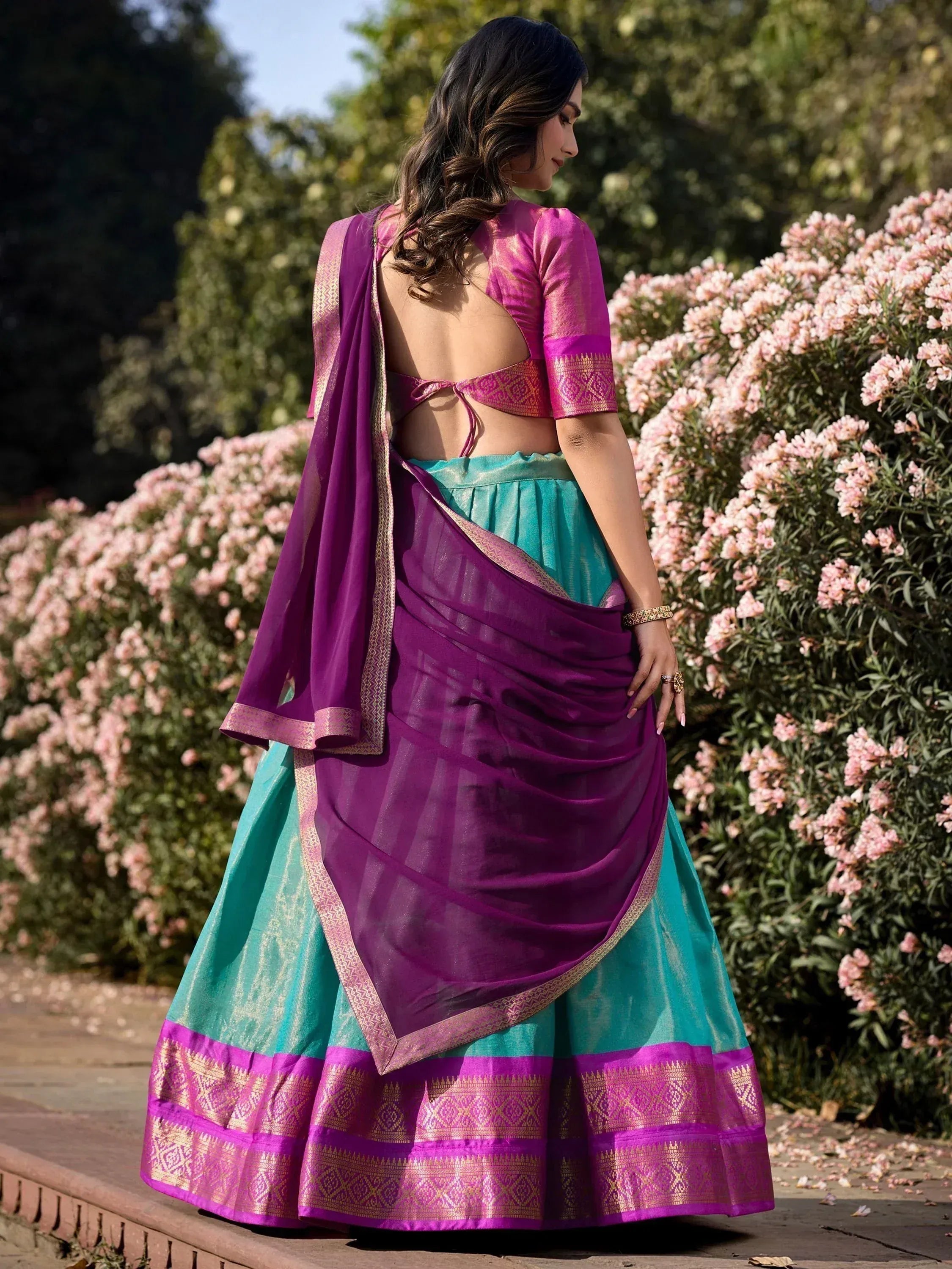 Purple and teal designer lehenga choli with gold border, backless blouse, floral garden setting