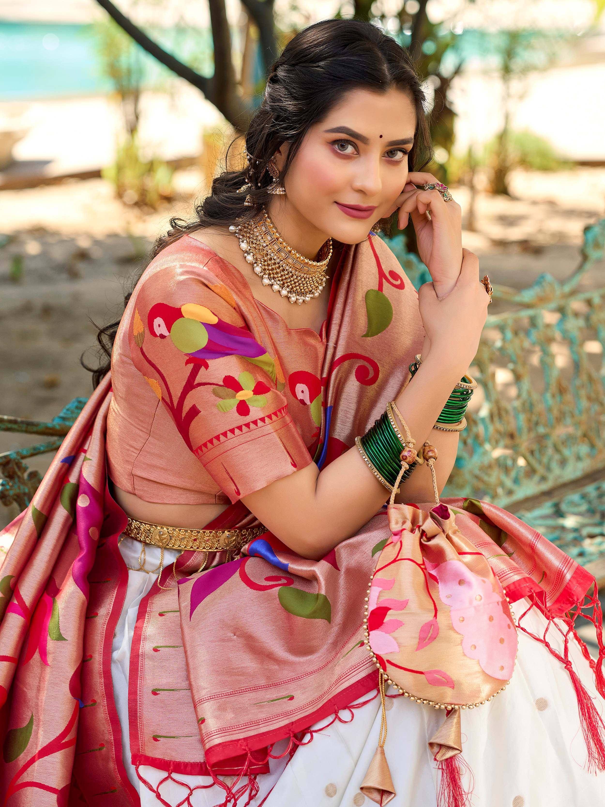 Woman in vibrant pink embroidered lehenga choli with parrot print, gold jewelry, and matching potli bag