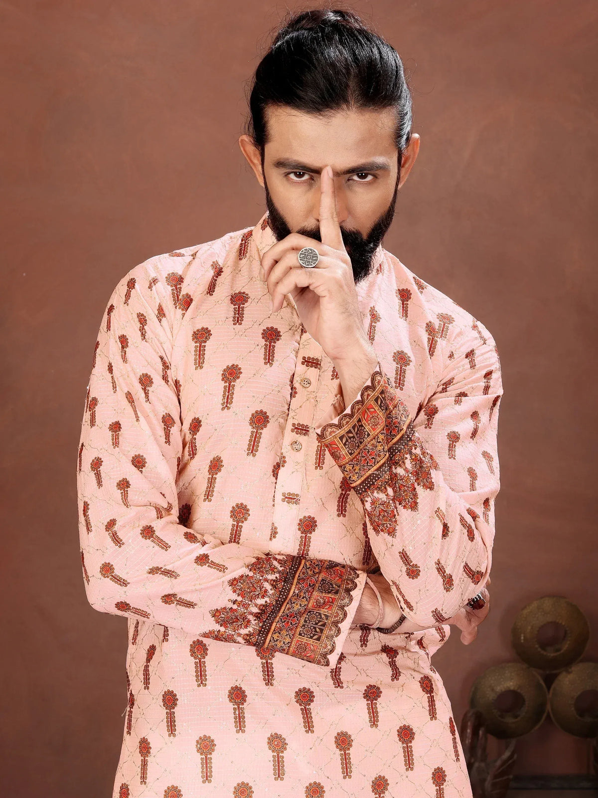 Man wearing a peach-colored embroidered ethnic kurta with detailed cuff patterns.