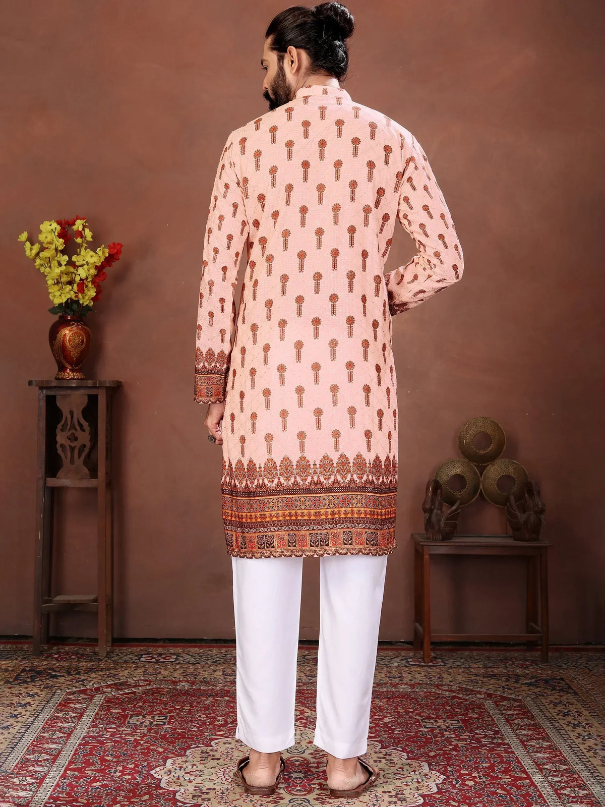 Back view of a man wearing a peach printed ethnic kurta with white trousers.
