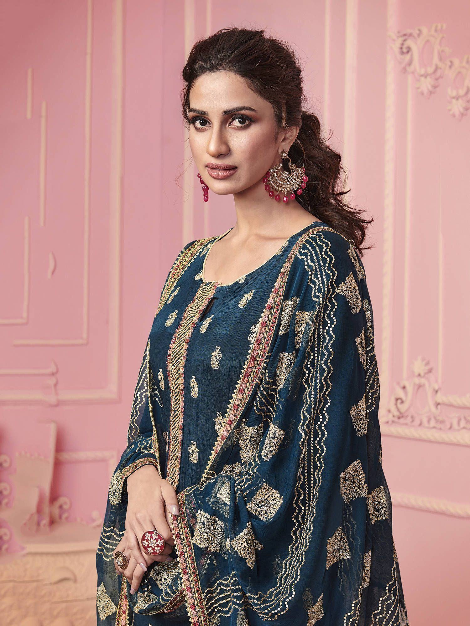 Woman in navy blue embroidered ethnic gown with statement earrings, posing indoors