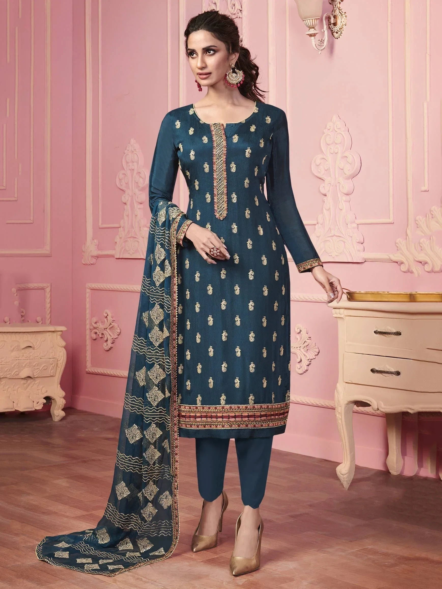 Woman wearing a navy blue embroidered salwar kameez with gold dupatta in elegant setting