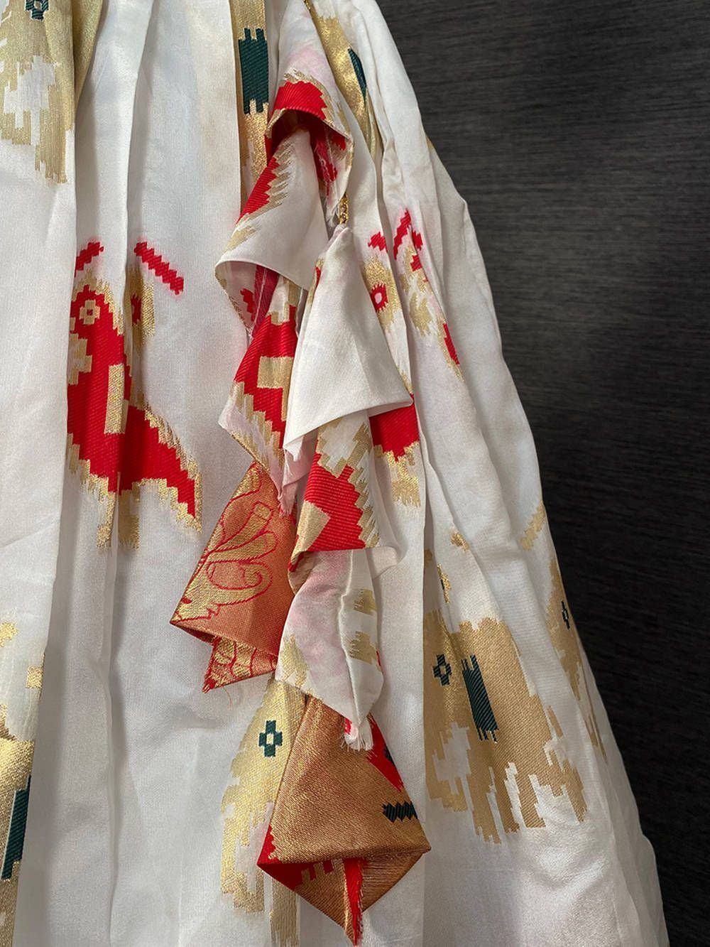 White ethnic saree with red and gold ikat patterns, perfect for Indian festive occasions