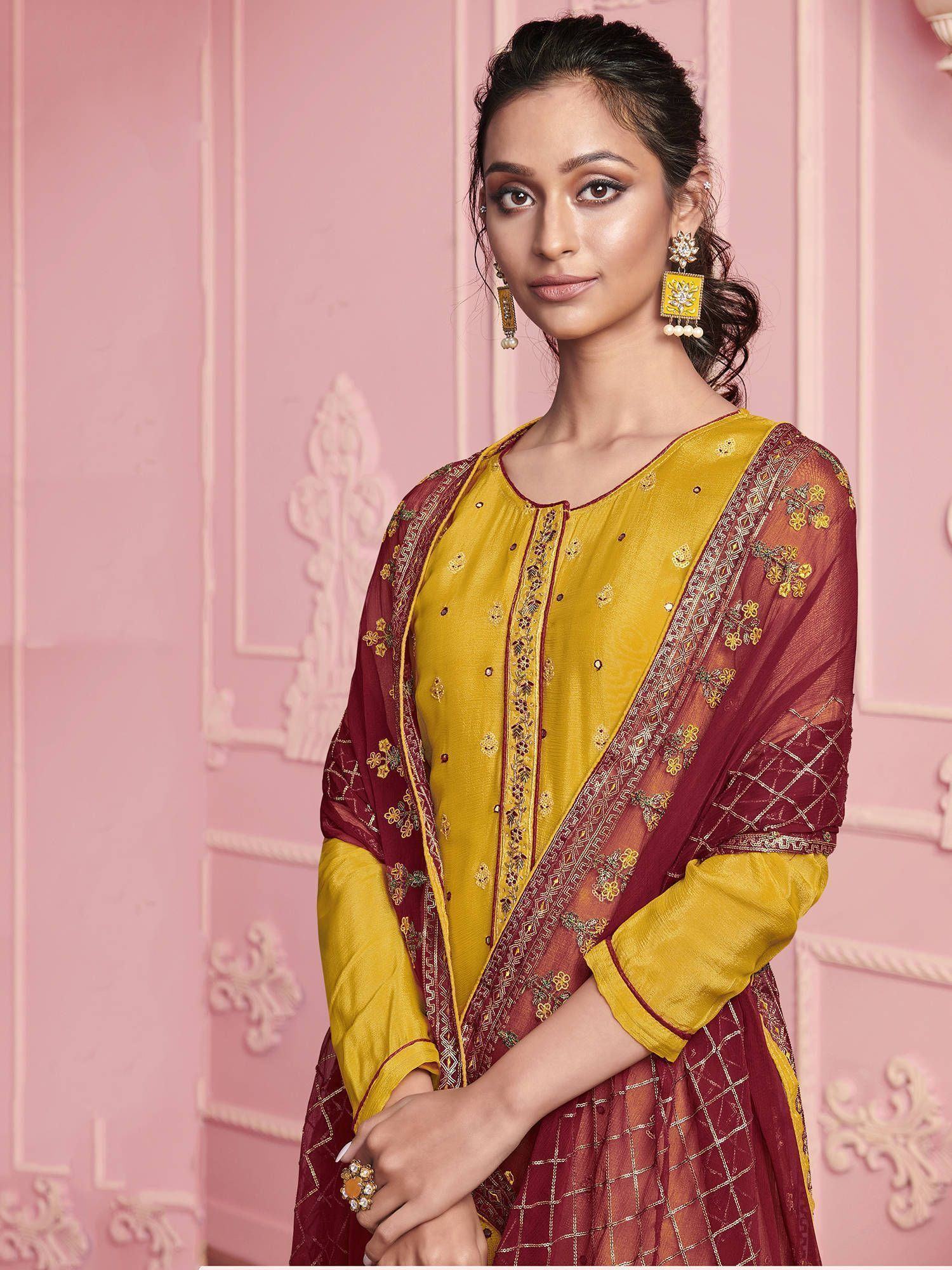 Woman wearing yellow and maroon embroidered salwar kameez with dupatta, traditional jewelry