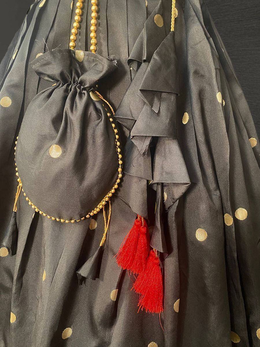 Black ethnic gown with gold polka dots, ruffles, red tassels, and matching drawstring pouch