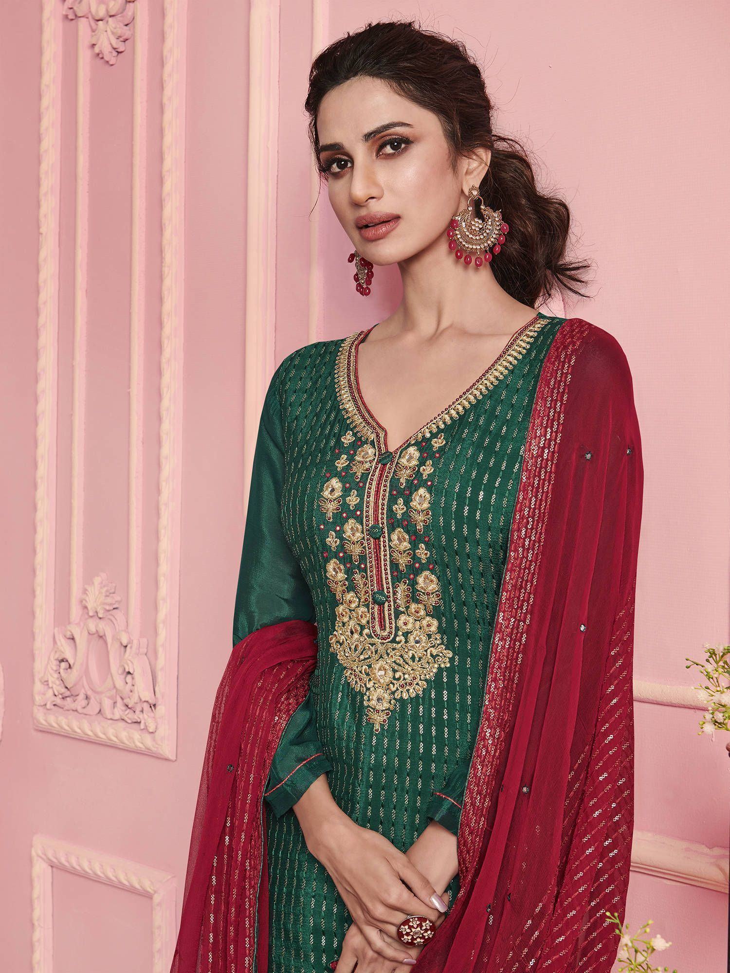 Woman wearing green embroidered salwar kameez with red dupatta and statement earrings