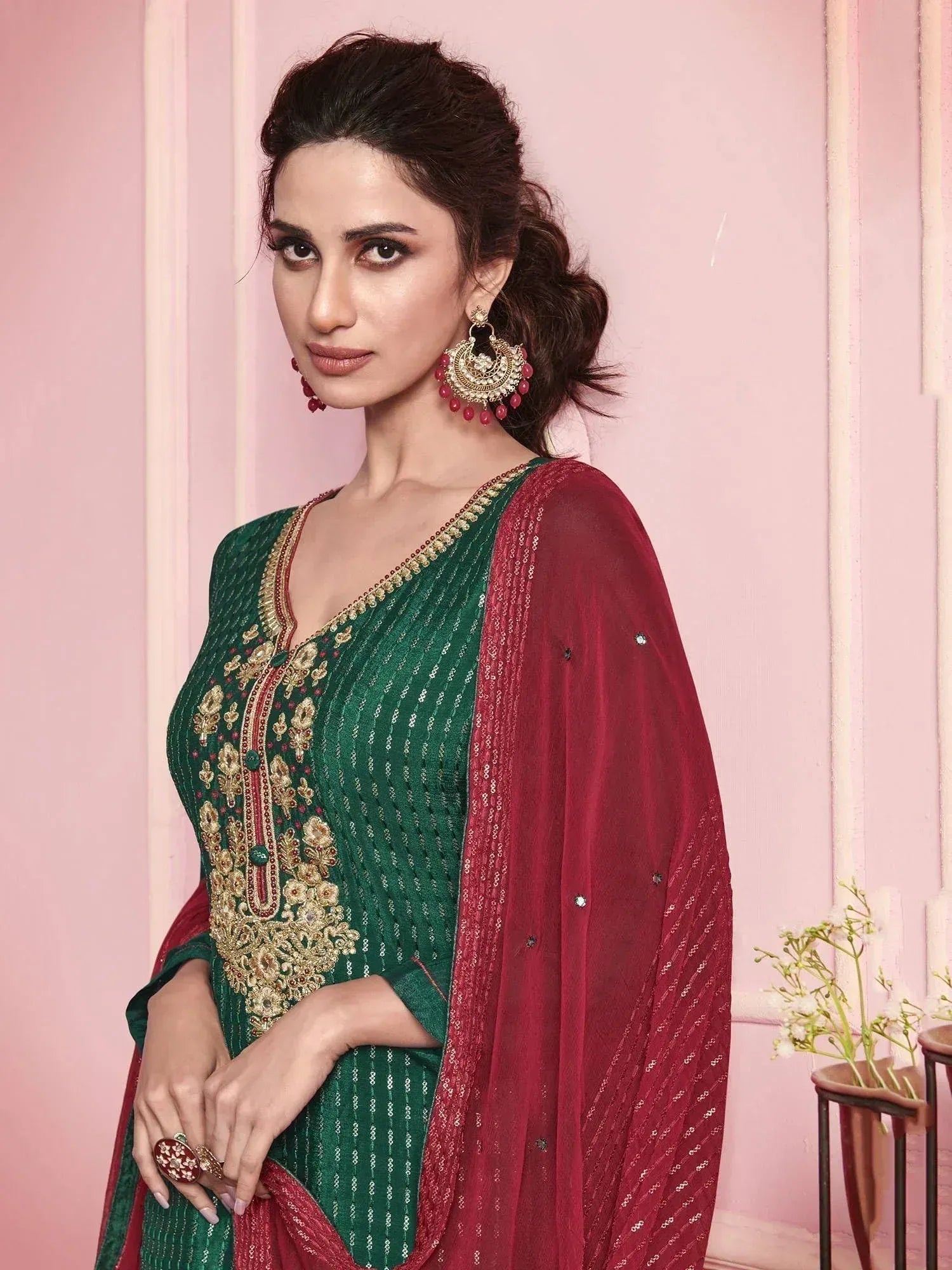Woman in green embroidered salwar kameez with maroon dupatta and statement earrings