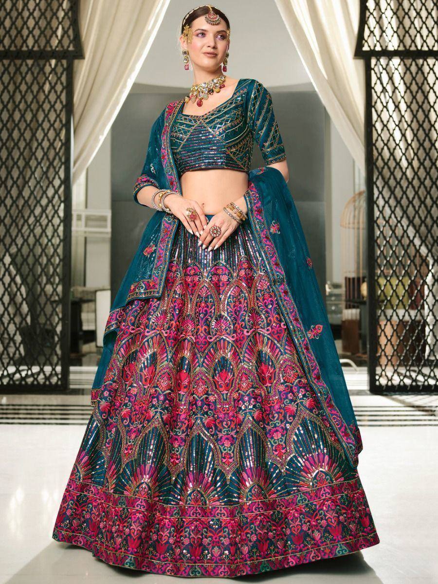 Teal and pink embroidered lehenga choli with heavy mirror work, perfect for Indian weddings and festive occasions.