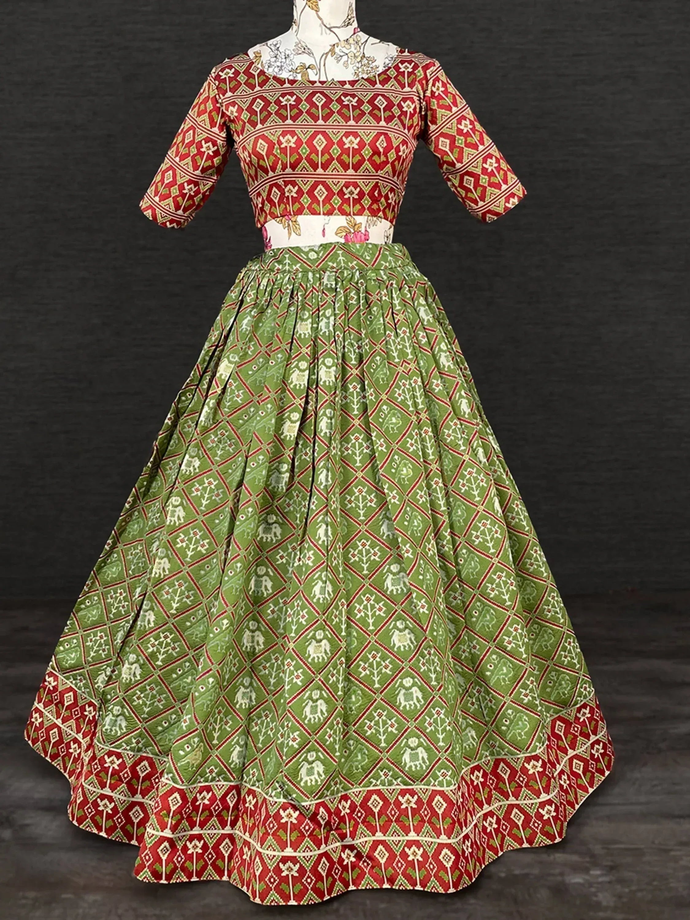 Red and green printed ethnic lehenga choli with floral and elephant motifs, perfect for festive occasions.