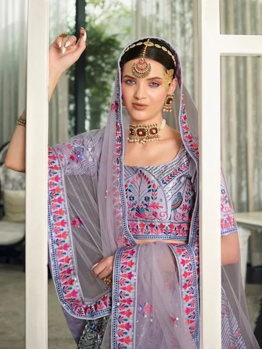 Purple embroidered lehenga choli with floral patterns and matching dupatta, styled with traditional jewelry