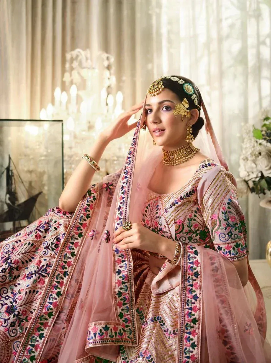 Elegant pink embroidered lehenga choli with gold jewelry, perfect for Indian weddings and festive occasions.