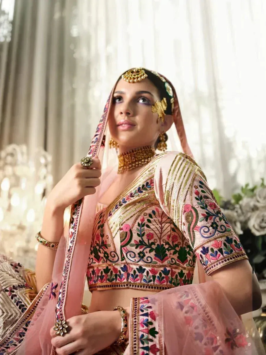 Pink embroidered lehenga choli with gold jewelry and floral motifs, perfect for Indian weddings and festive occasions.
