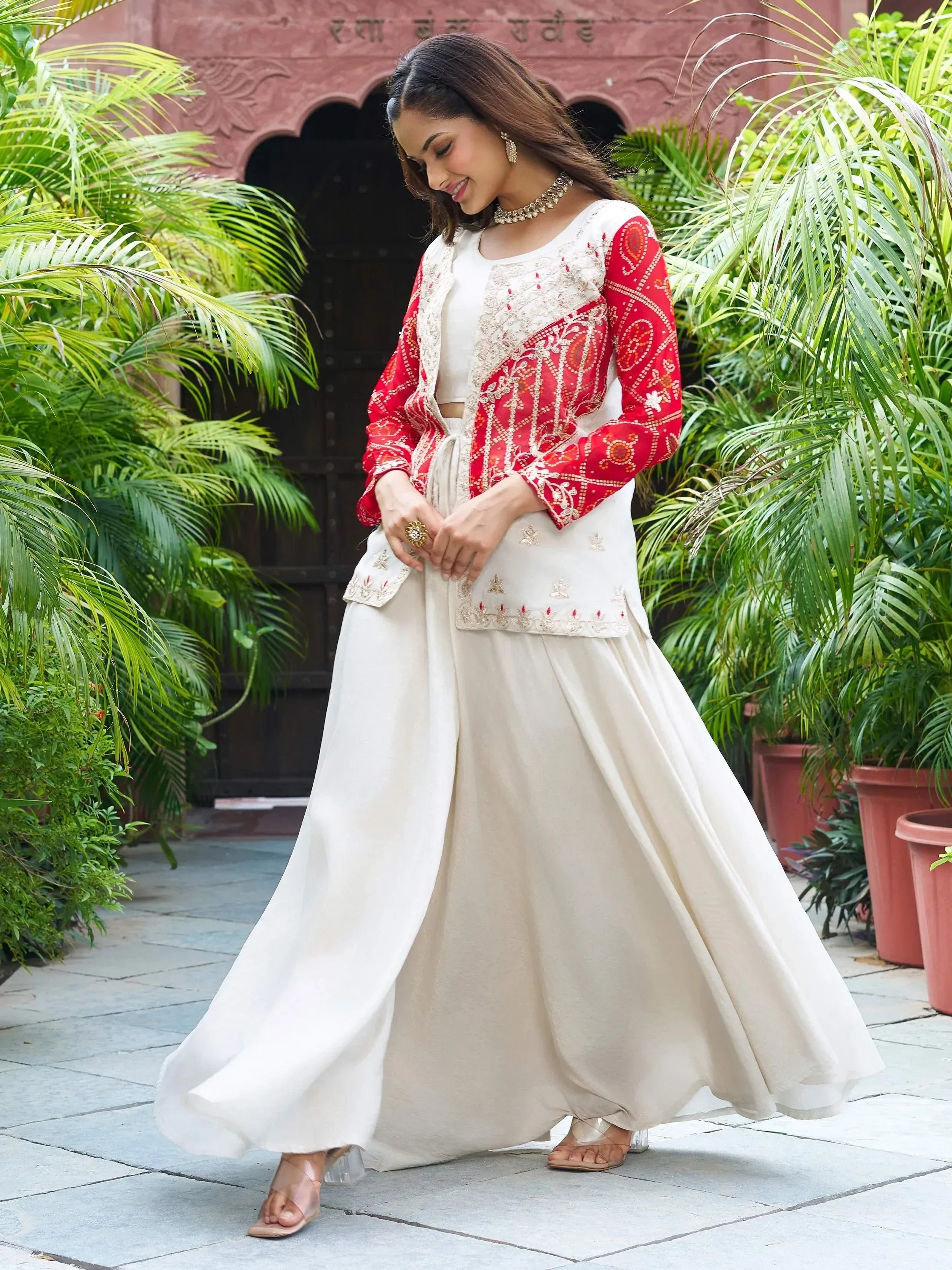 Woman in white ethnic gown with red embroidered jacket, perfect for Indian occasions and festive wear.