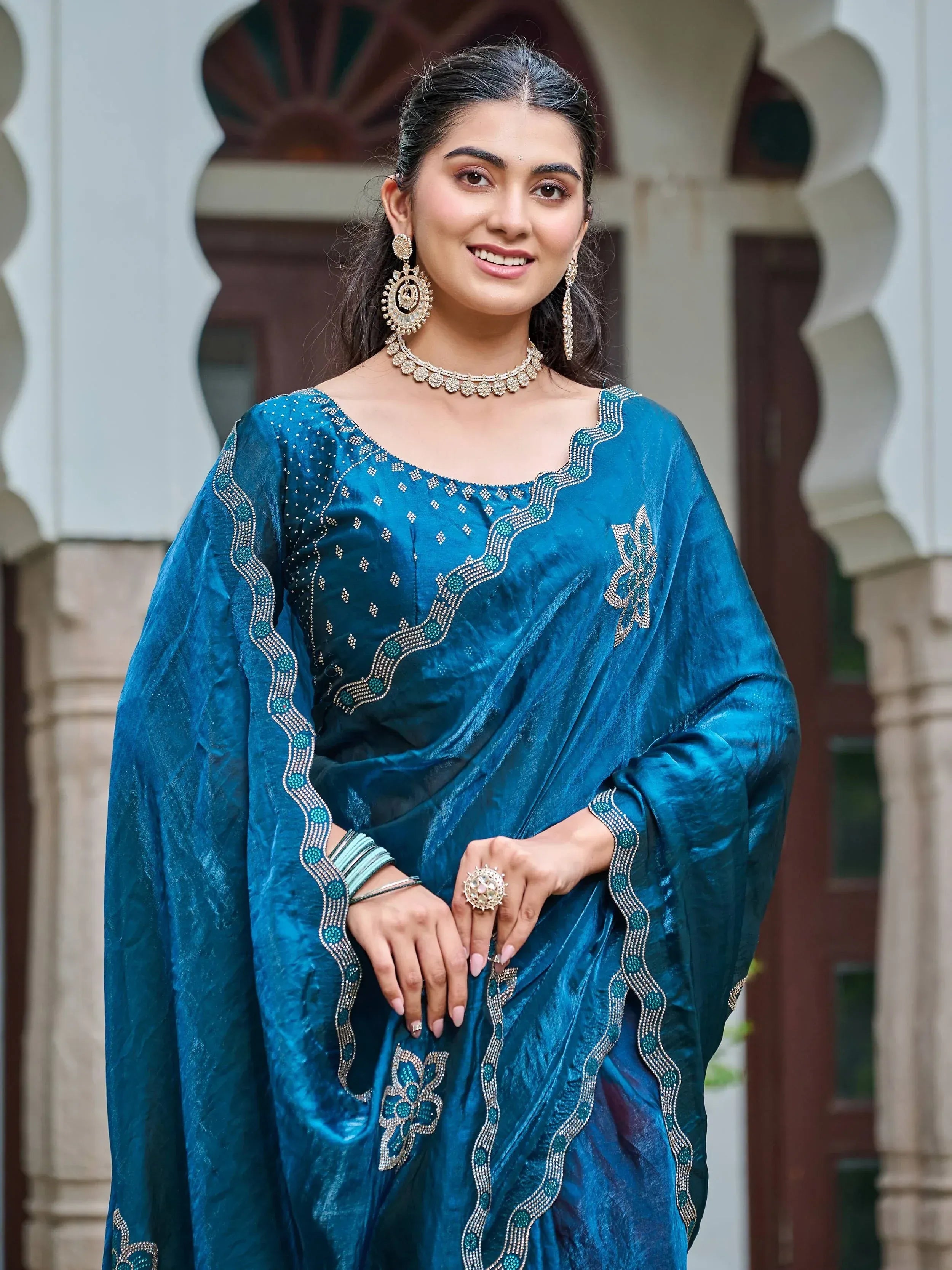 Woman in teal embroidered Indian ethnic gown with traditional jewelry, perfect for festive occasions.