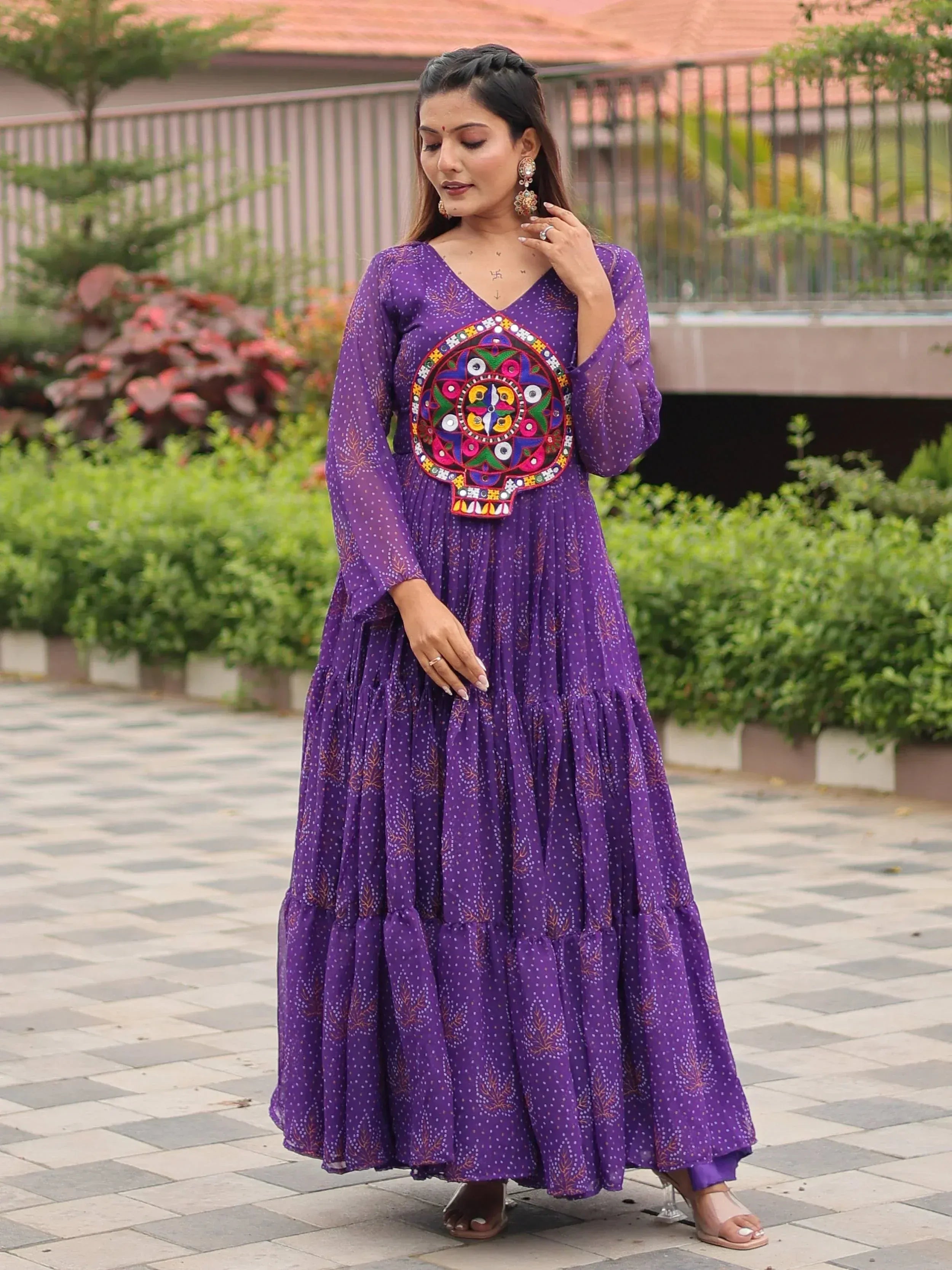 Purple ethnic gown with colorful mirror work and tiered skirt, perfect for festive occasions.
