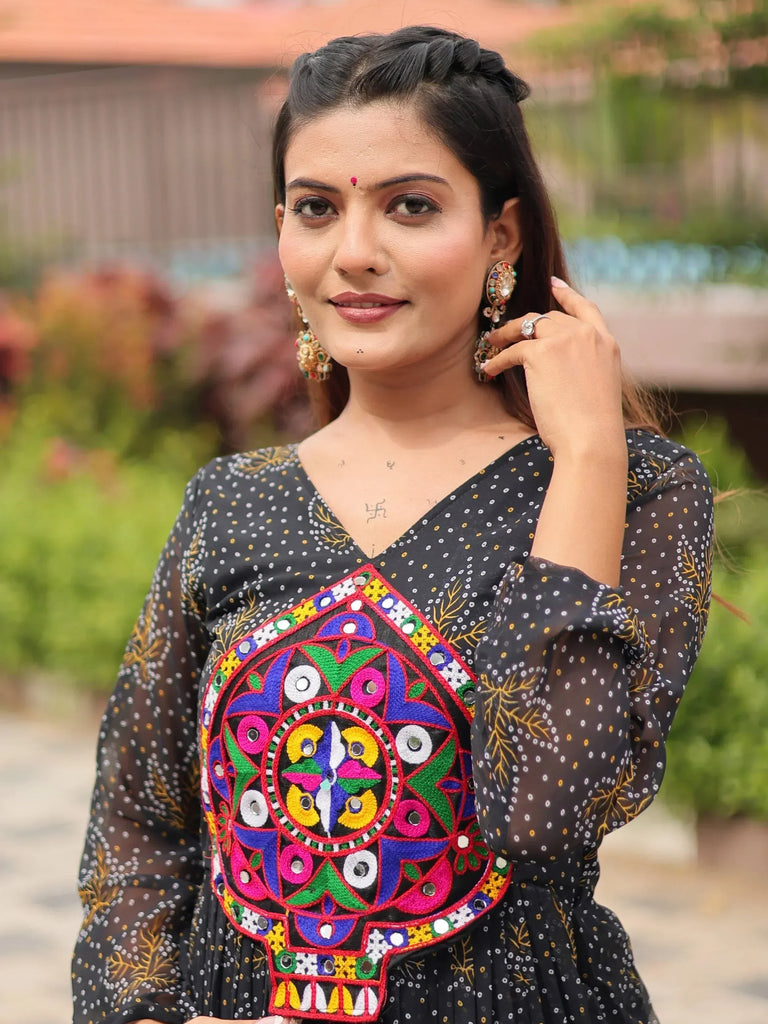 Woman in black ethnic gown with colorful mirror work embroidery, perfect for Indian festive occasions.