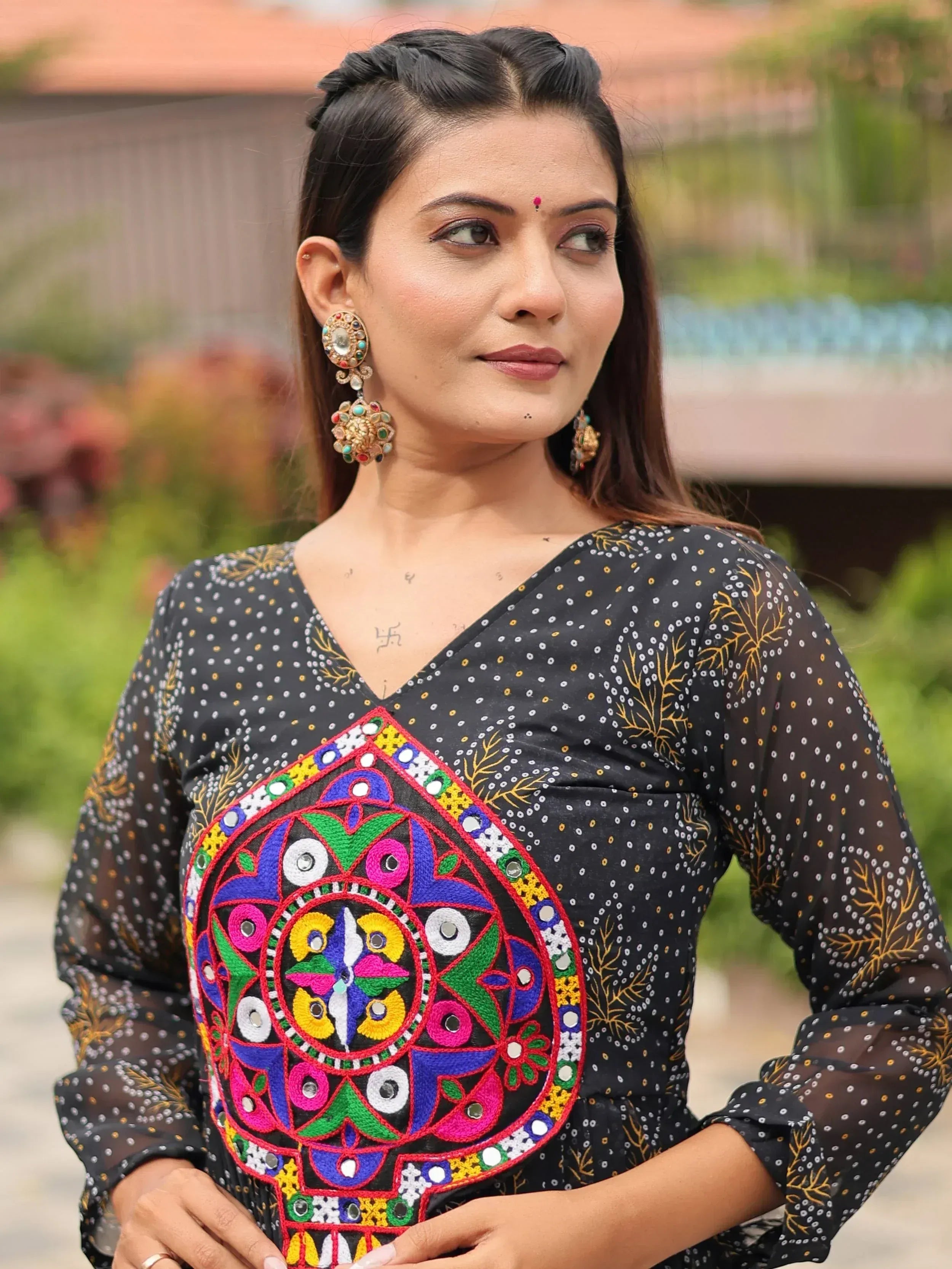 Woman in black ethnic kurti with colorful mirror embroidery and statement earrings, perfect for Indian festive wear.