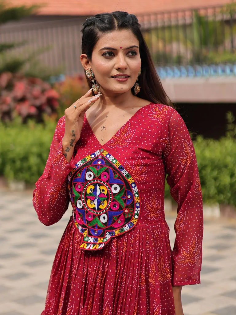 Woman in red ethnic gown with colorful mirror embroidery, perfect for Indian festive occasions.