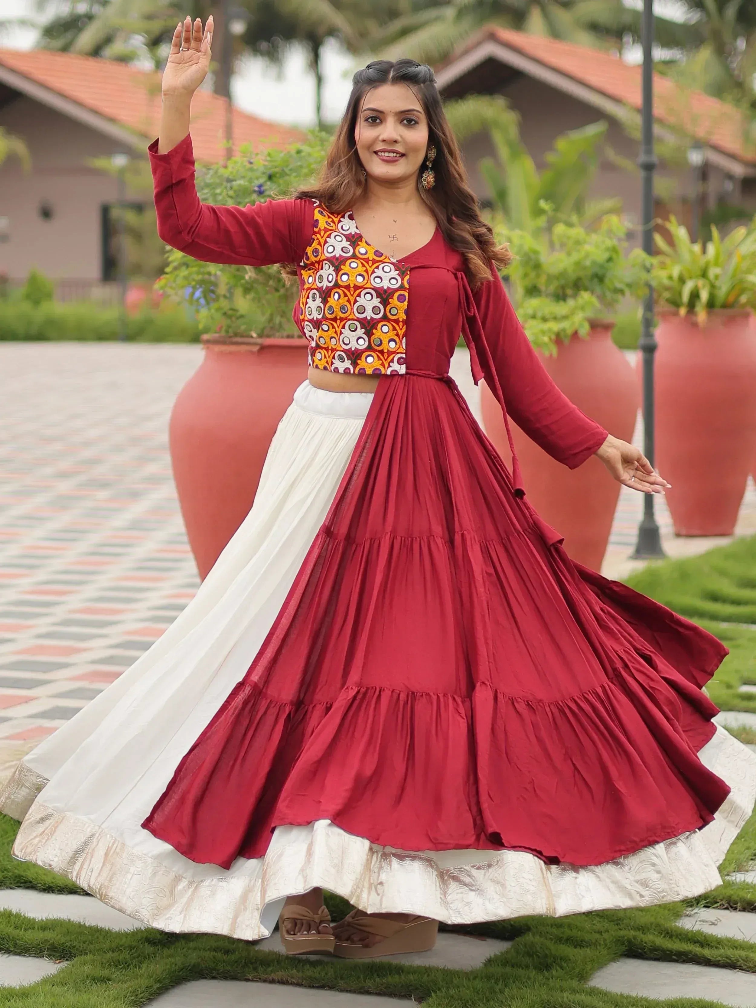 Woman in maroon and white embroidered lehenga choli with floral top, twirling outdoors