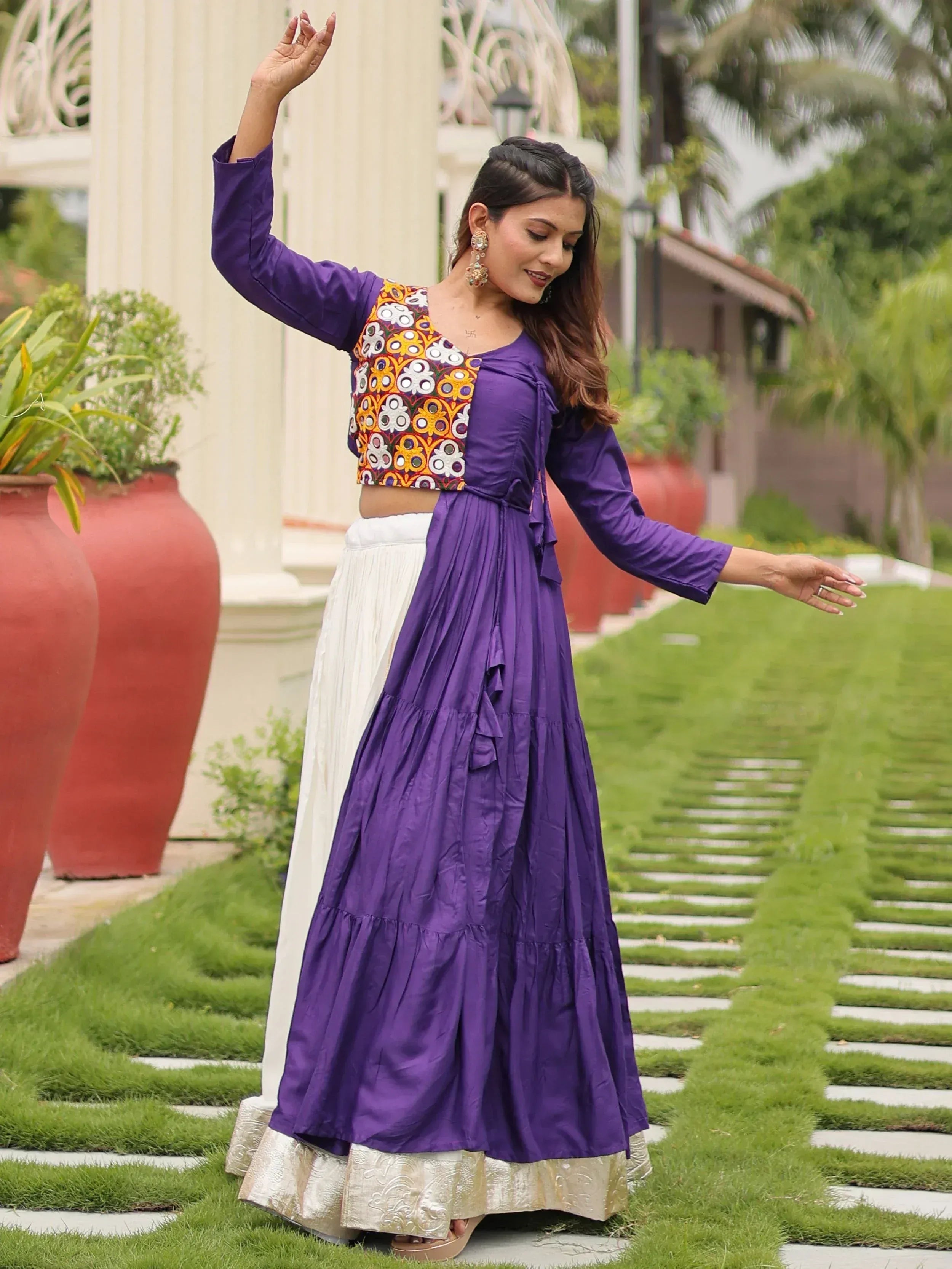 Woman in purple embroidered crop top and white skirt, Indian ethnic wear, garden setting