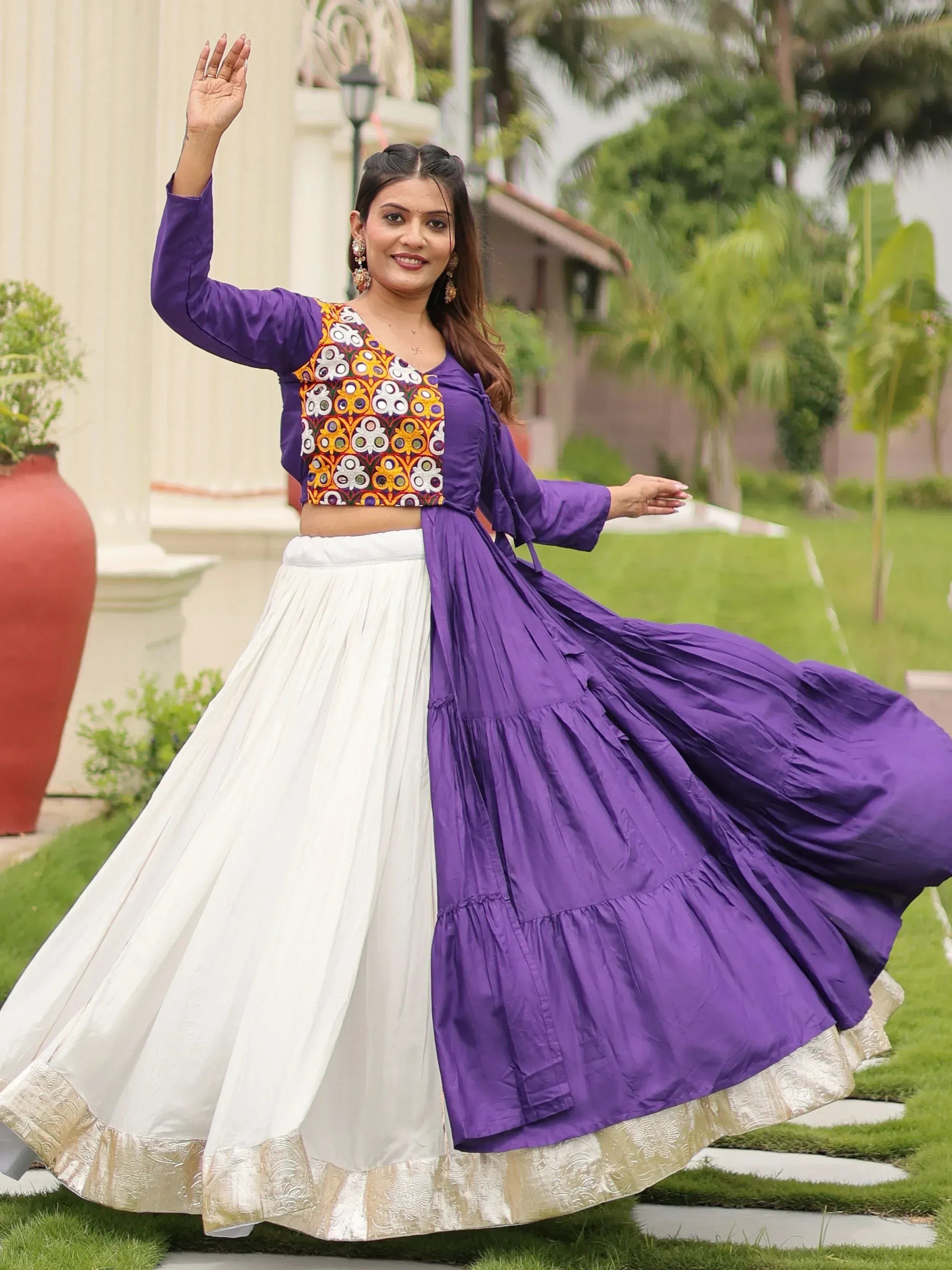 Woman in purple and white ethnic lehenga with embroidered crop top, twirling outdoors