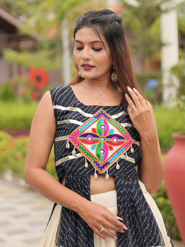 Woman in black and white striped ethnic top with colorful mirror work and shell embellishments, paired with cream skirt