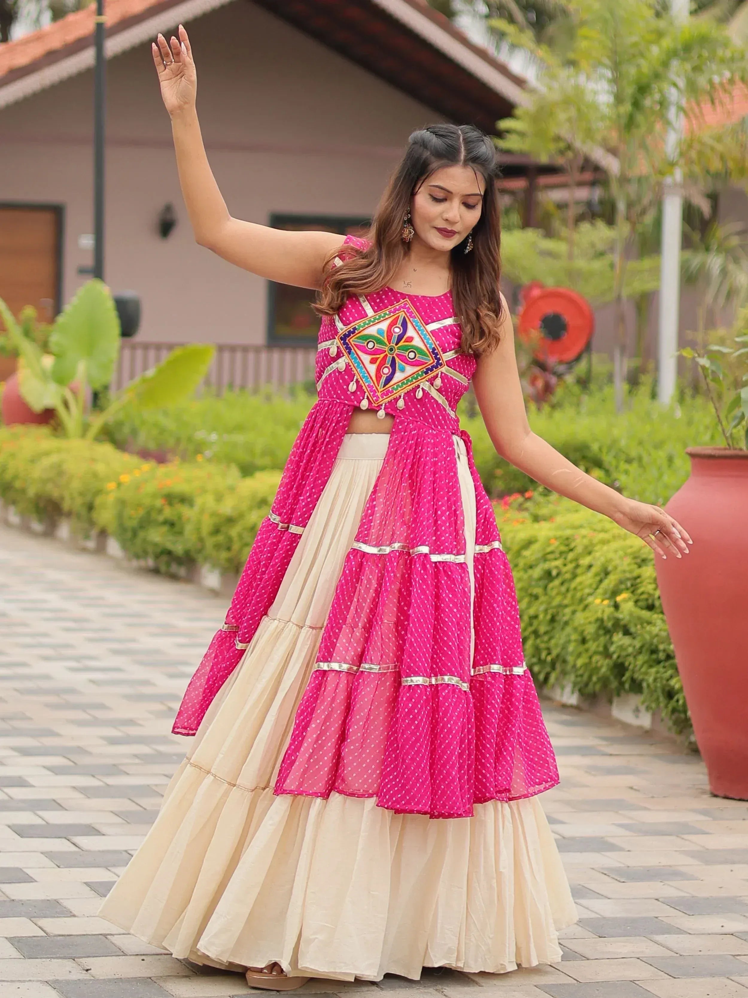 Woman in pink and cream ethnic lehenga choli with mirror work, perfect for Indian festivals and weddings.