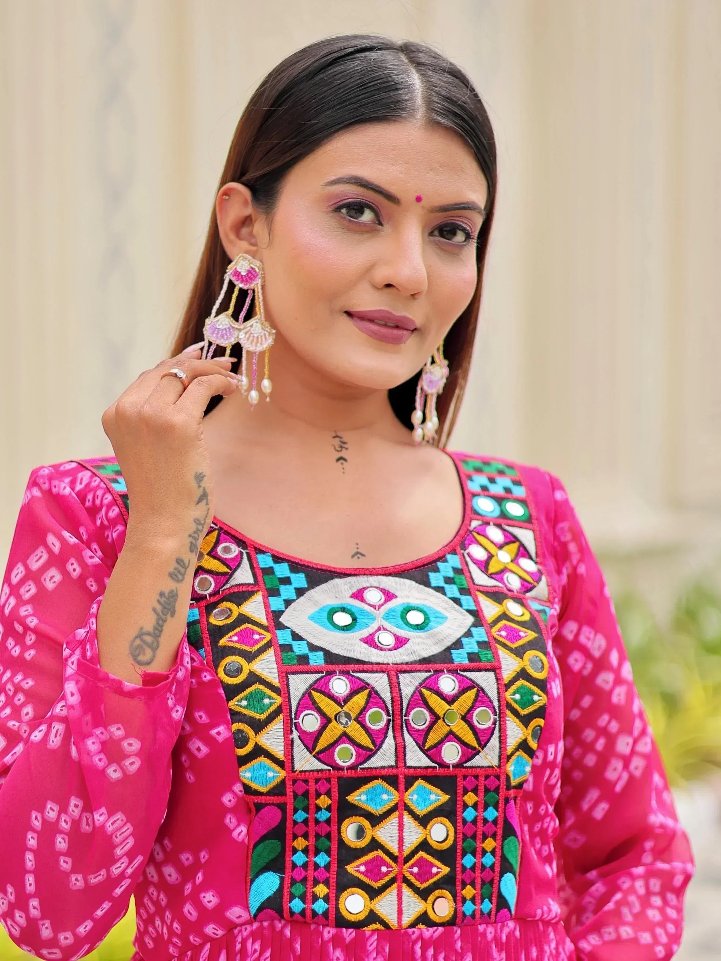 Woman in vibrant pink ethnic kurta with mirror embroidery and statement earrings, showcasing Indian designer wear