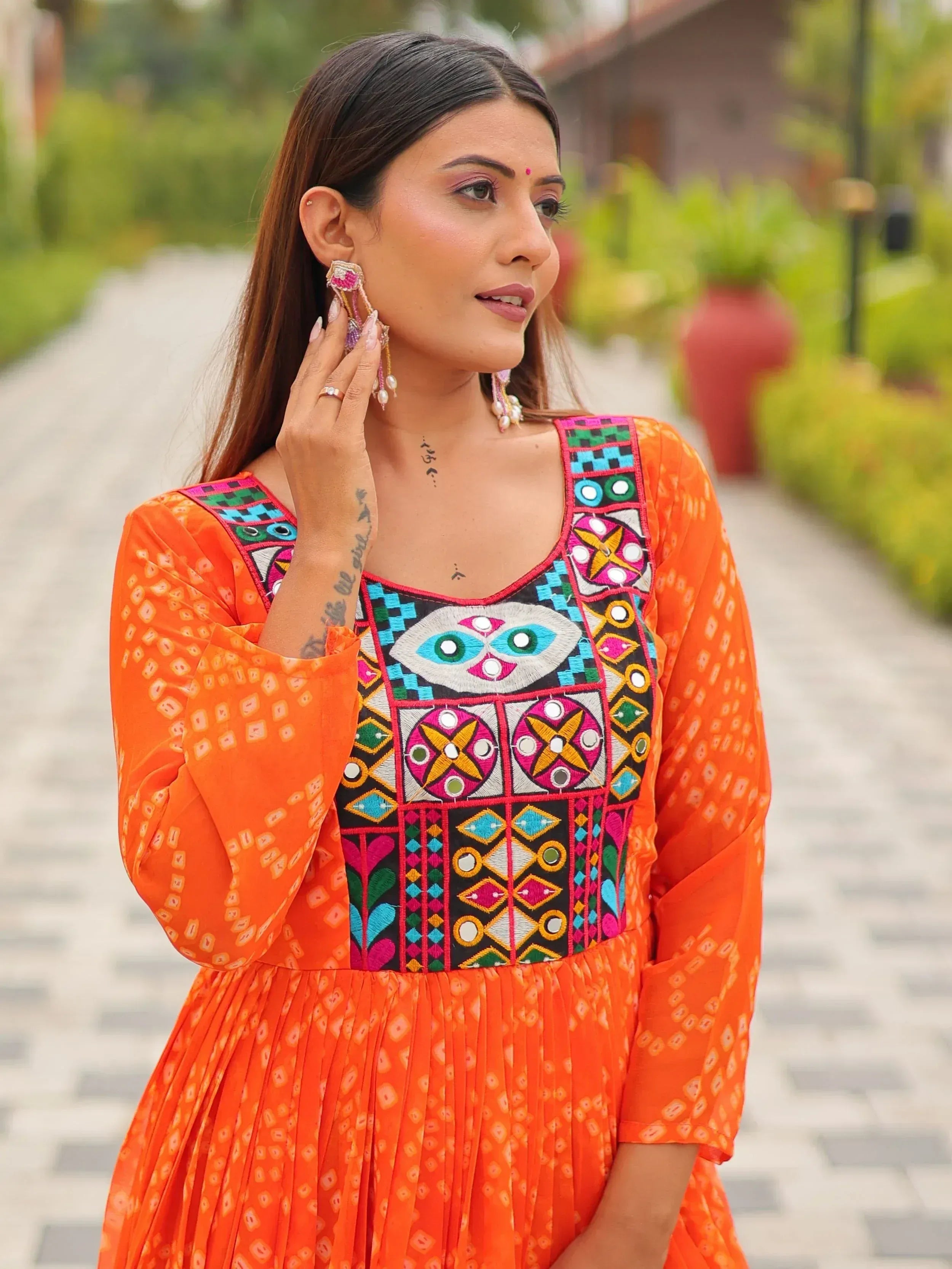 Orange ethnic gown with colorful mirror embroidery and geometric patterns, perfect for Indian festive wear.