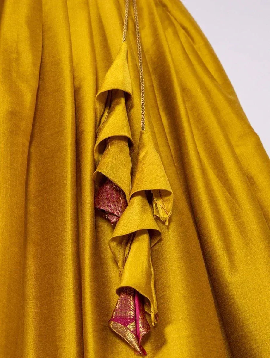 Mustard yellow ethnic gown with ruffled detailing and pink gold accents, perfect for festive occasions.