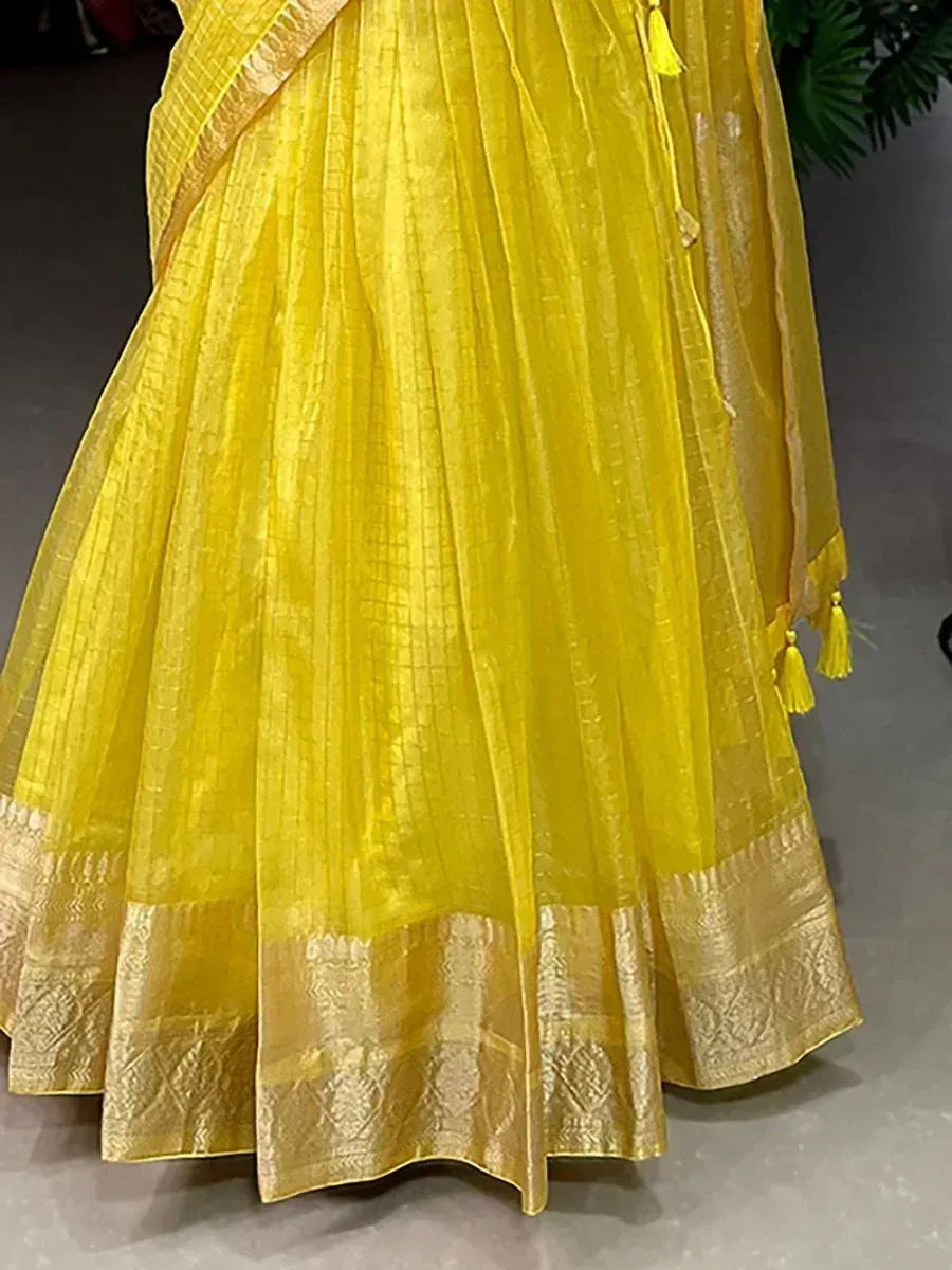 Yellow ethnic lehenga with golden border and tassels, perfect for Indian weddings and festive occasions