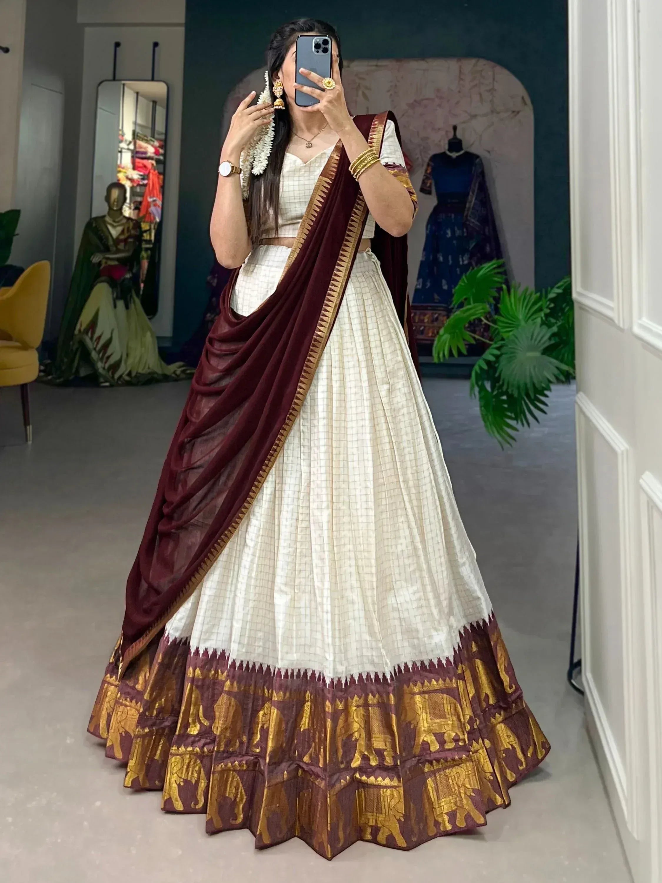 Woman in white checkered lehenga choli with maroon dupatta, gold elephant border, traditional Indian ethnic wear