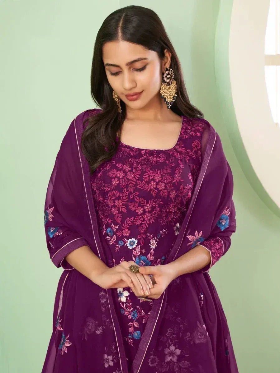 Woman in purple floral embroidered salwar kameez with dupatta and statement earrings