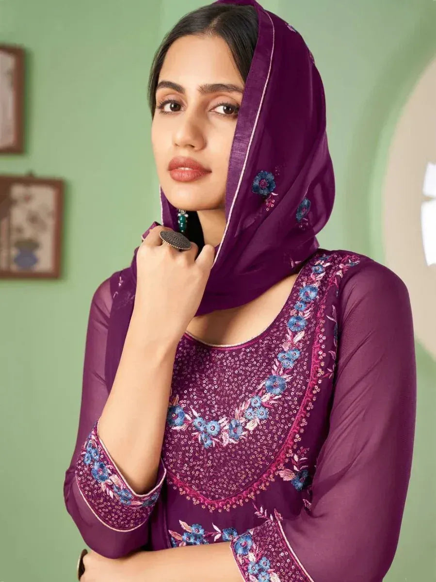 Woman in purple embroidered salwar kameez with matching dupatta, floral detail, indoors