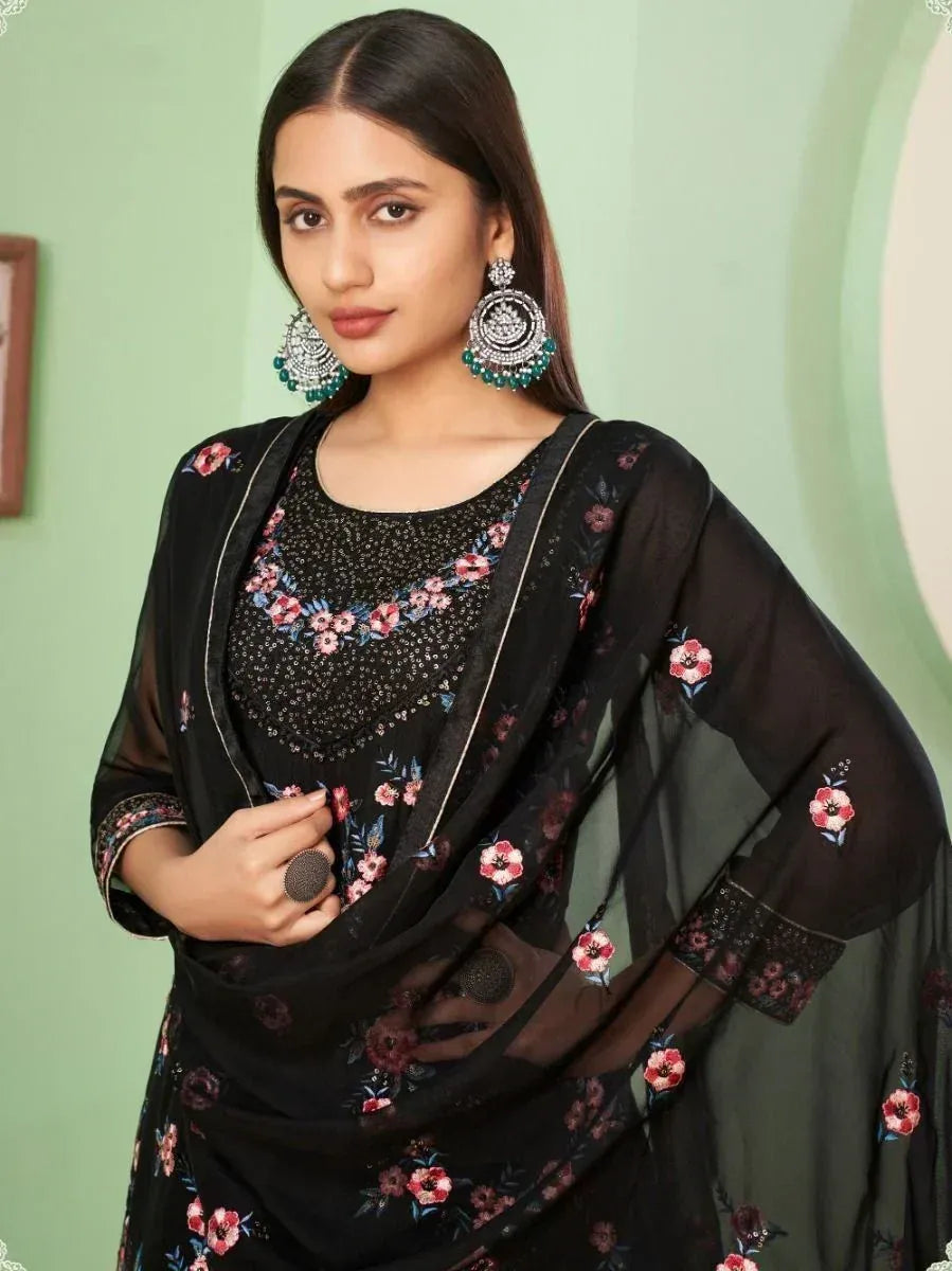 Woman wearing black floral embroidered salwar kameez with matching dupatta and statement earrings