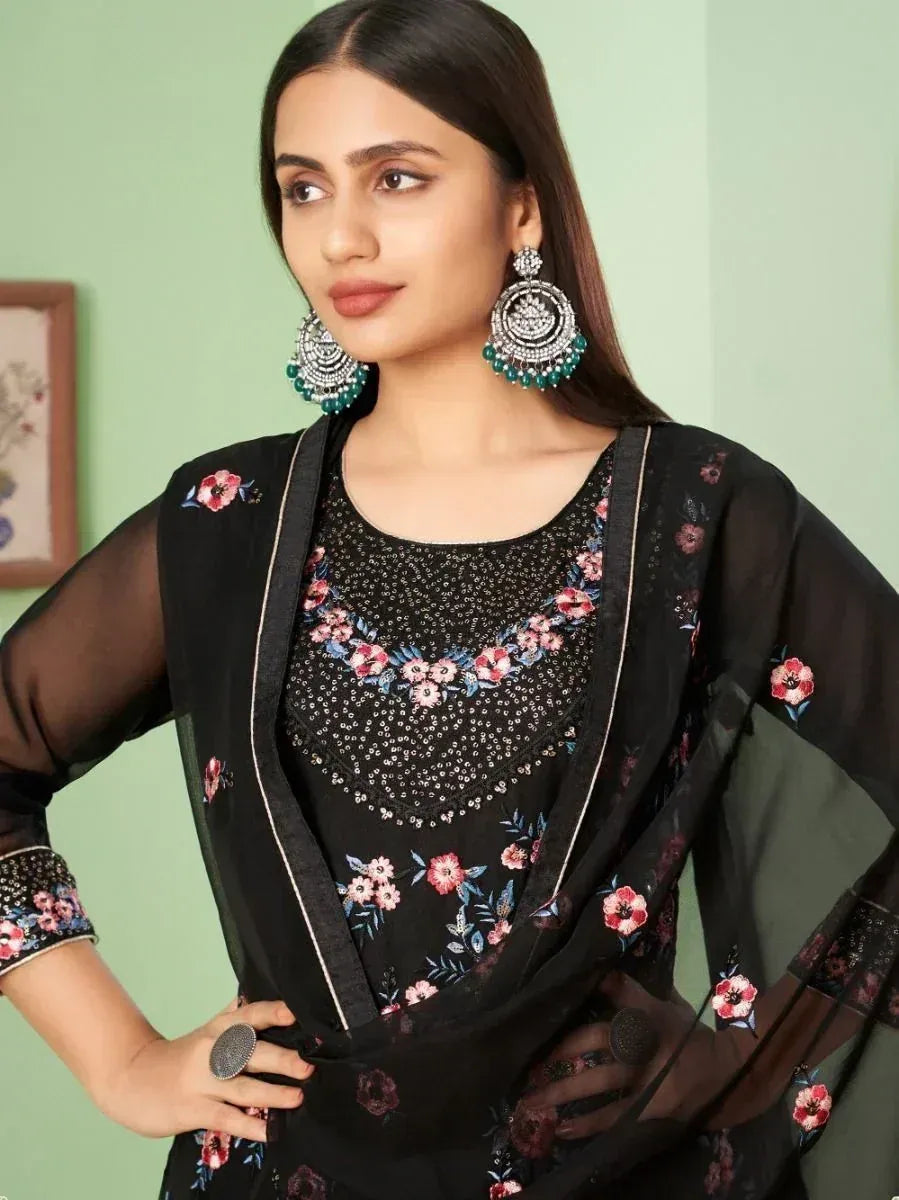 Woman in black floral printed salwar kameez with sheer dupatta and large ethnic earrings