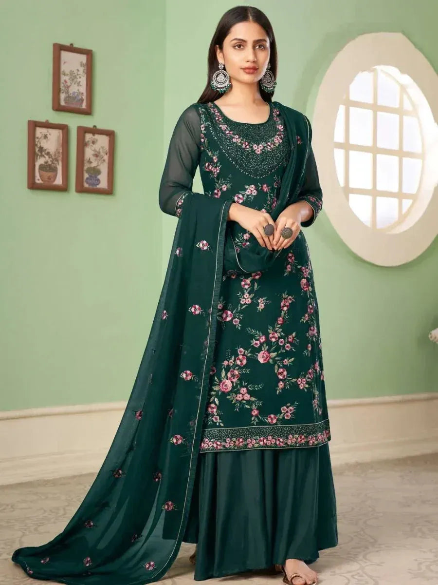 Woman wearing a dark green floral embroidered salwar kameez with dupatta in a light room