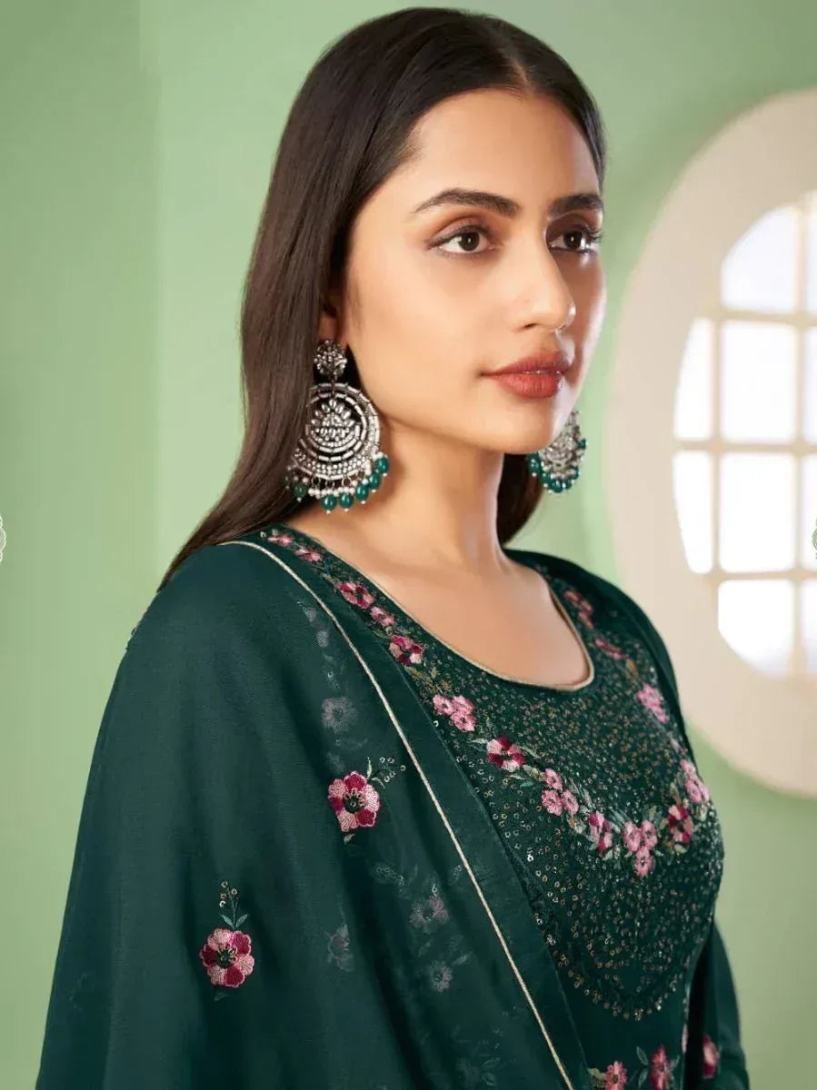 Woman in dark green embroidered ethnic salwar kameez with floral patterns and statement earrings