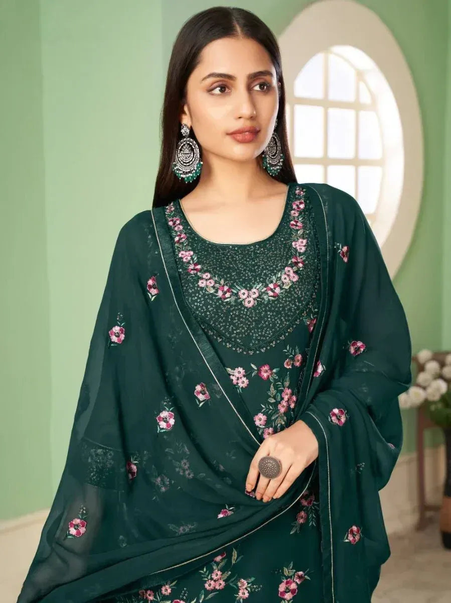 Woman in green floral embroidered salwar kameez with dupatta and statement earrings