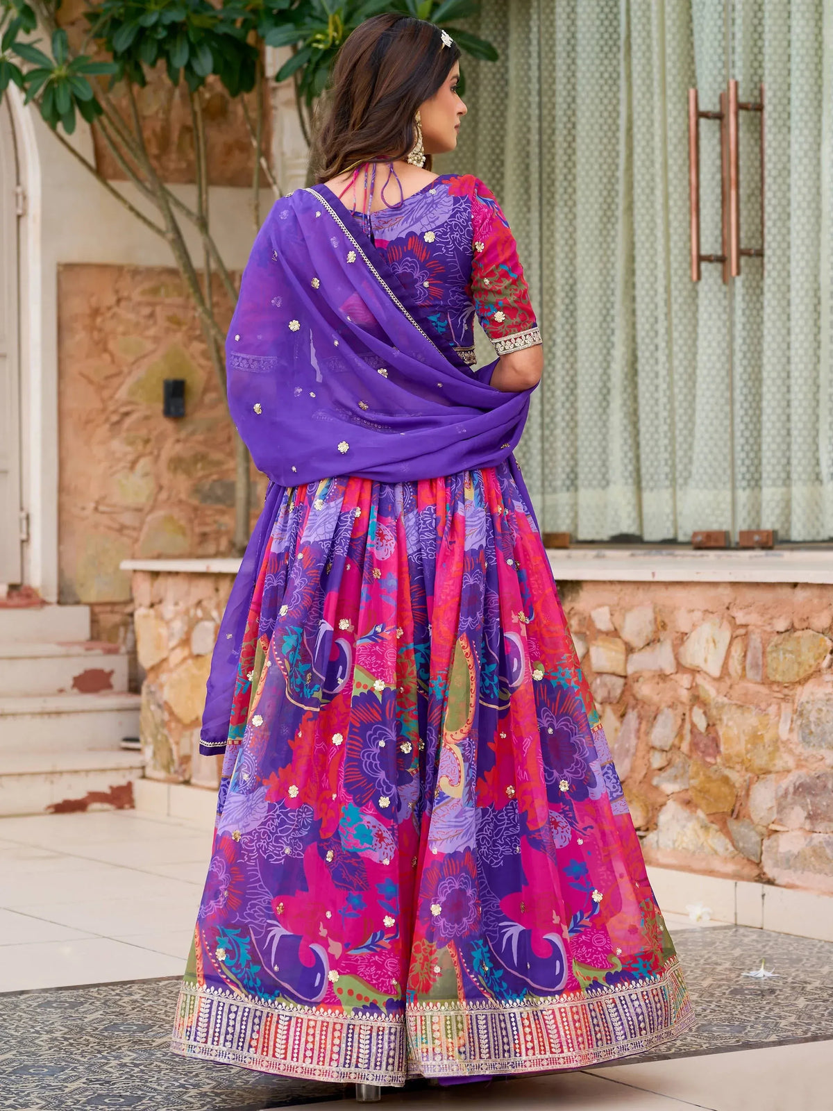 Vibrant purple and pink printed lehenga choli with floral motifs and gold embellishments, perfect for festive occasions.