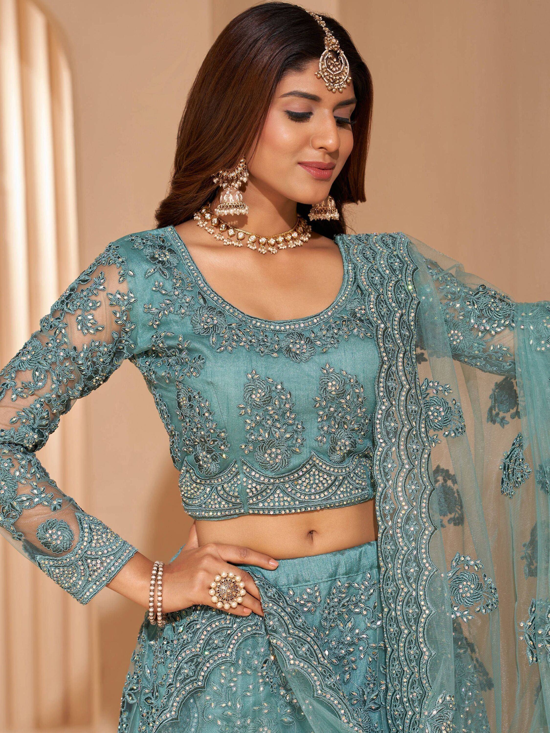 Teal embroidered lehenga choli with sheer sleeves and matching dupatta, styled with traditional Indian jewelry.