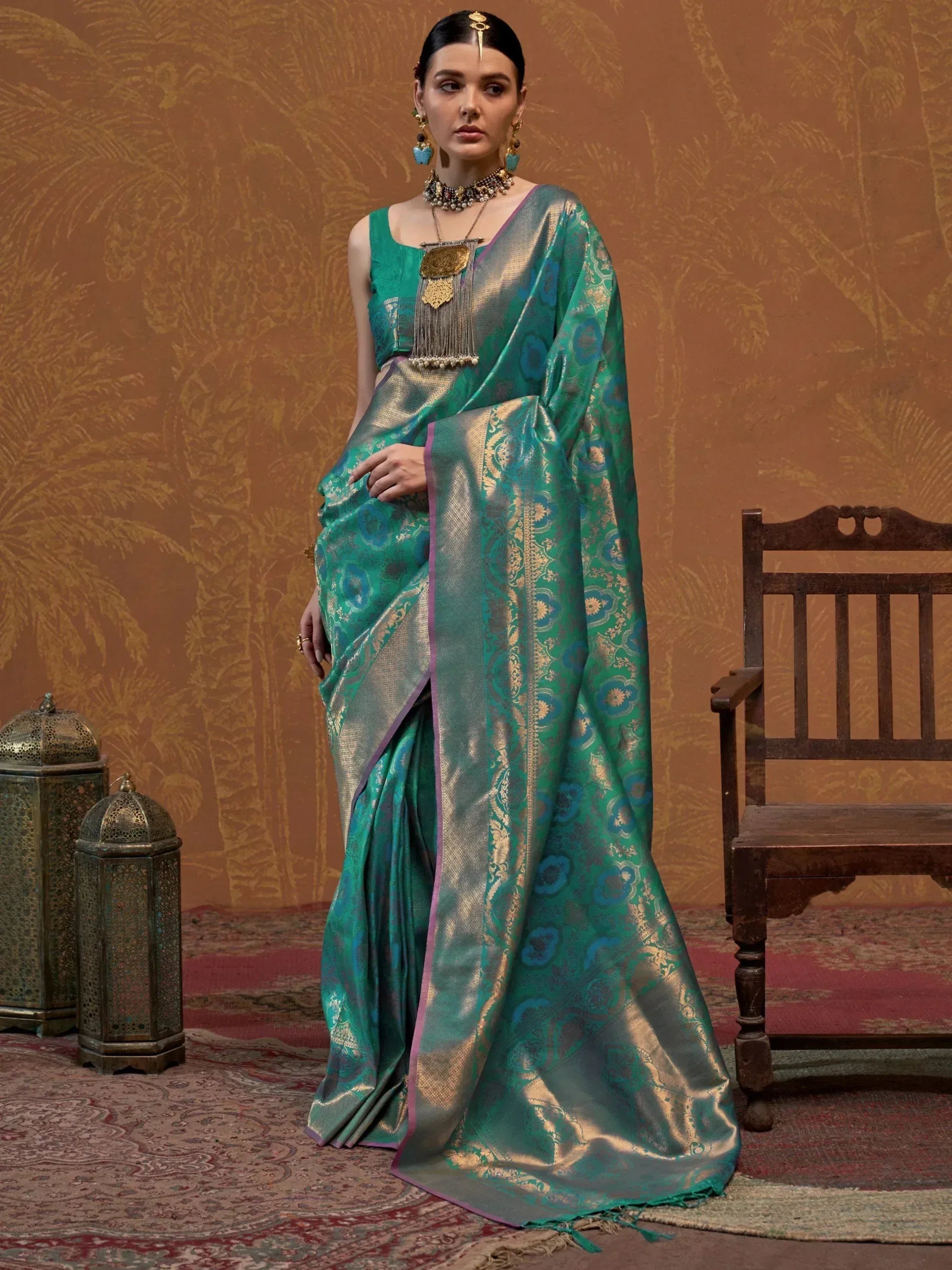 Elegant teal silk saree with gold floral motifs and purple border, paired with designer blouse and traditional jewelry.