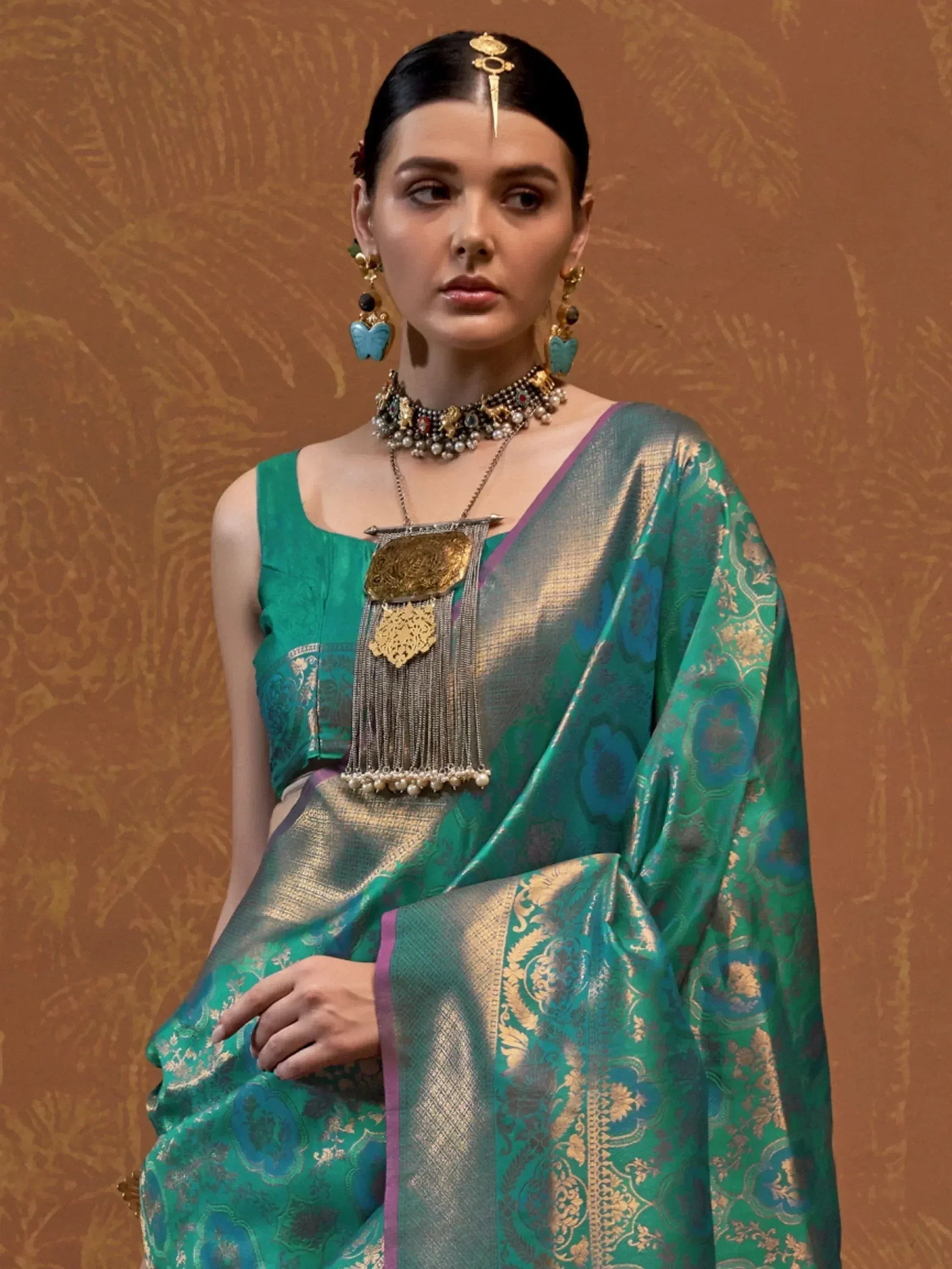 Elegant teal and gold designer saree with intricate patterns and traditional jewelry for Indian ethnic wear