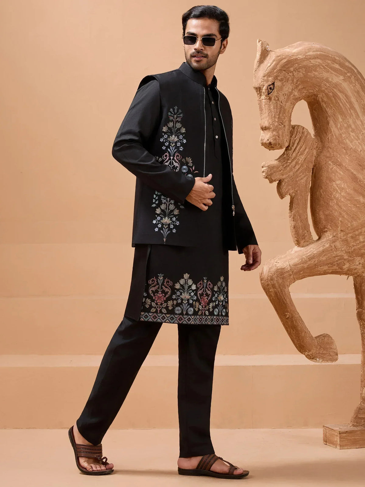 Black embroidered kurta set with floral motifs, styled with sunglasses and sandals for men's ethnic wear.