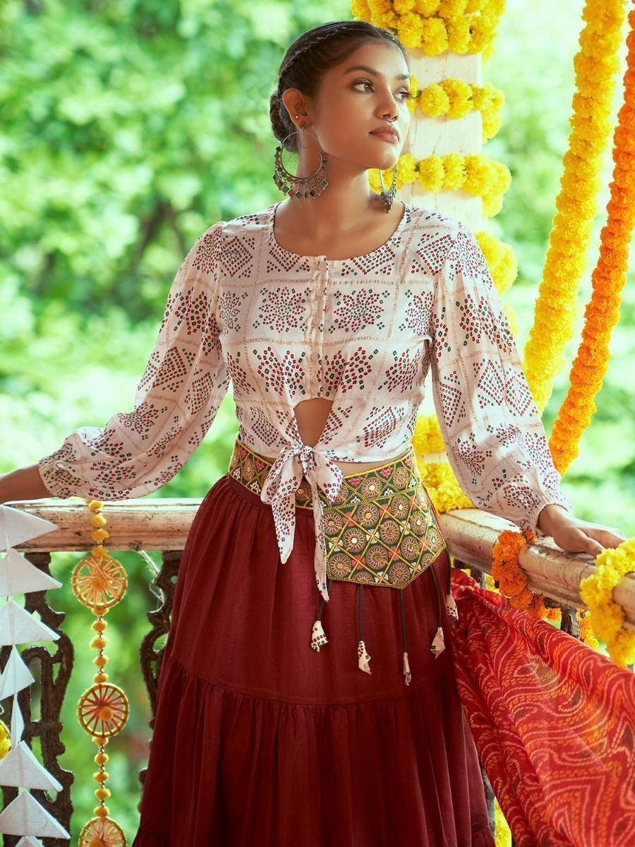 Woman in embroidered ethnic top and maroon skirt with floral garlands, perfect for Indian festive wear