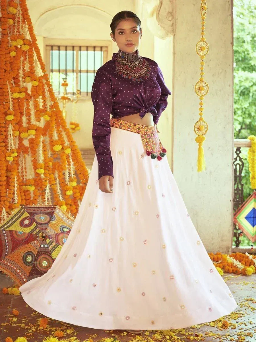 Woman in purple polka dot crop top with white embroidered lehenga, festive marigold decor