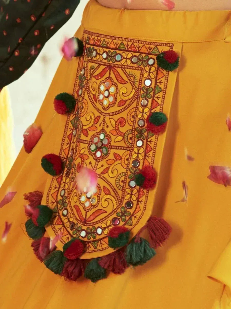 Yellow ethnic skirt with mirror work, pom-poms, and tassels for festive Indian wear